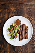 Grilled beef steak with basil and vegetable serving on plate with BBQ sauce