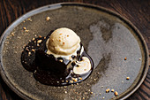 Chocolate brownie cake with milk ice cream and crushed nuts on plate