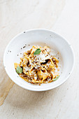 Dish with wide pasta sprinkled with cheese and decorated with fresh mint