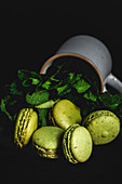Homemade green macarons with mint on dark background