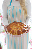 A woman holding a baking pan with bread rolls