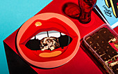 A piece of tiramisu on a plate with a pop art lip motif