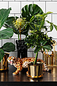 Leopardenfigur und exotische Pflanzen in goldenen Übertöpfen