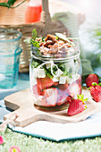 Salad with strawberries, feta and arugula in a glass for a picnic