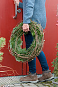 Woman brings wreath from Nordmann fir and wild wine tendrils