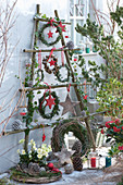Weihnachtlich dekorierte Terrasse mit Kränzen, Sternen, Zapfen und Lichtern an selbstgebautem Gestell aus Ästen