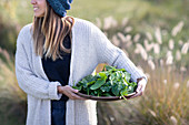 Frau hält Holzschale mit frischem Spinat