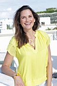 A young woman wearing a yellow sleeveless top