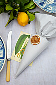 Papiertüte mit Anhänger aus getrockneter Zitronenscheibe als Tischdekoration