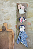 Organiser made from enamel mugs on wooden board leaning against rustic stone wall
