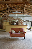 Sofa in front of counter in old barn with chipboard panels on floor