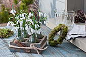 Small bouquets with snowdrops in wooden boxes, wreath of moss