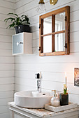 Washstand with round countertop sink in bathroom with white wooden wall