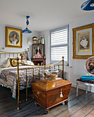 Antique wooden trunk at foot of metal bed in classically decorated bedroom