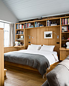 Bed in niche surrounded by fitted wooden shelves