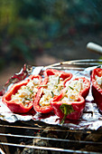 Grilled red pointed peppers filled with feta cheese and rosemary on a barbecue