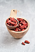 Goji berries in a wooden bowl and a wooden scoop