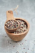 Coloured quinoa in a wooden bowl and a wooden scoop