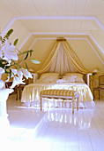 Opulentes Bett mit Baldachin und Rüschen im Dachzimmer