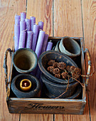Purple candles and rustic plant pots in old wooden crate