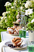Muffins und Bügelflasche mit Minzsirup auf dem Gartentisch