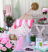 Cushions in hammock and arrangements of pink flowers on terrace