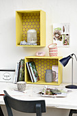 Shelf modules made from wooden crates painted yellow above desk