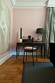 Black chair at Baroque console table against pink wall