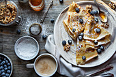 Crepes with blueberries, walnuts, honey and icing sugar for breakfast