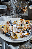 Crepes with blueberries, walnuts, honey and icing sugar for breakfast