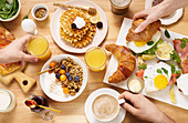 Gesundes Sonntagsfrühstück mit Croissants, Waffeln, Müsli und Sandwiches