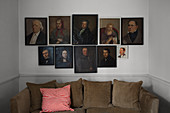 Antique portraits hung along horizontal axis above sofa