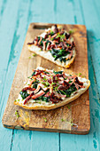 Unleavened-bread pizza with dried tomatoes, spinach and ham