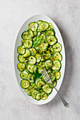 Quick sweet vinegar pickle sliced cucumber salad with dill, peppercorn, bay leaves and mustard seeds