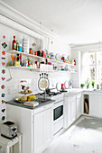 White kitchen-dining room with brightly coloured accents on shelves