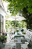 Dining table and parasol on summery terrace outside house