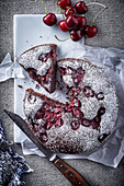 Cherry cake dusted with icing sugar, a piece cut