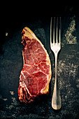 A raw rump steak with a fork