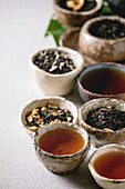 Stillleben mit verschiedenen Teesorten, aufgebrüht und als Teeblätter