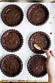 Chocolate tartlets being made: tart bases being spread with chocolate