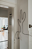 Electrical cable whimsically pinned to the wall in the shape of a cactus