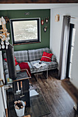 Tartan sofa against green wall and wood-burning stove in tiny house