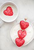 Weiße heiße Schokolade in Tassen dekoriert mit herzförmigen roten Marshmallows