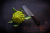 Fresh Romanesco with a knife on a dark surface