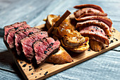 Fresh toasts with pieces of roasted and raw meat placed on wooden board