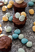 Chocolate cupcakes with mini chocolate eggs on a textured surface