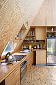 Fitted kitchen with sloping, wood-panelled wall