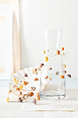 Delicate garland of wire and small seashells wound around carafe