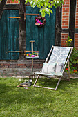 Deckchair wich cushions outside house with petrol-blue wooden doors