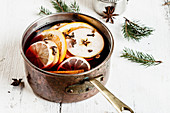 Mulled wine with fruit slices and spices in a copper pot
